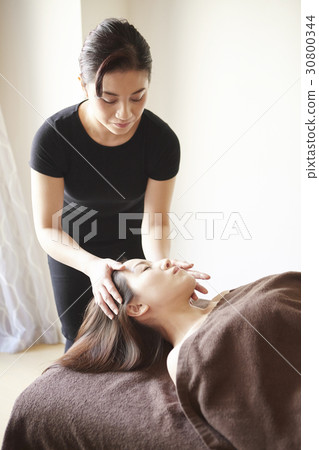 the therapist is focusing on massaging customer's head. the therapist is focusing on massaging customer's head. 30800344