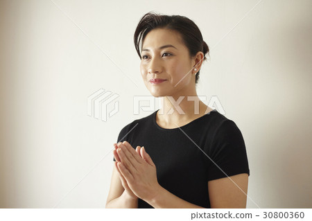 A portrait of woman clasping her hands 30800360