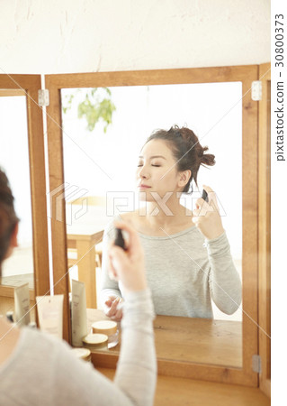 The woman is spraying mineral water on her face at home. The woman is spraying mineral water on her face at home. 30800373