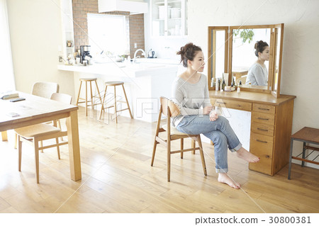 A woman is sitting in front of the mirror at home. A woman is sitting in front of the mirror at home. 30800381