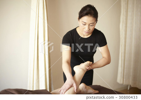 The therapist is massaging the leg of a woman in spa. 30800433