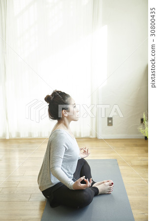 Young woman is sitting in a lotus position when practicing yoga. Young woman is sitting in a lotus position when practicing yoga. 30800435