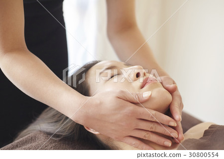 a woman is getting a facial massage in spa. 30800554