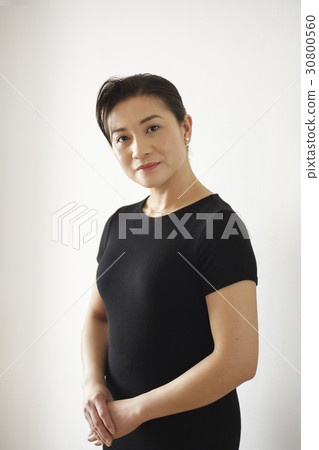 a portrait of a woman standing, holding hands and smiling. a portrait of a woman standing, holding hands and smiling. 30800560