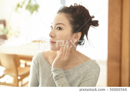 a woman glances and touches her cheek. 30800568