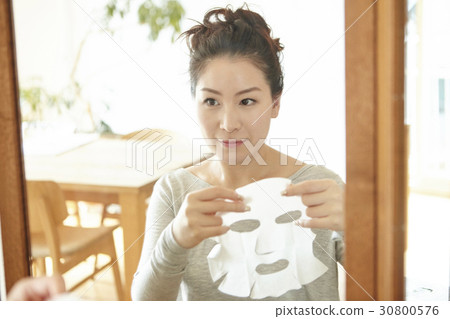 a woman prepares to apply facial mask sheet at home. 30800576