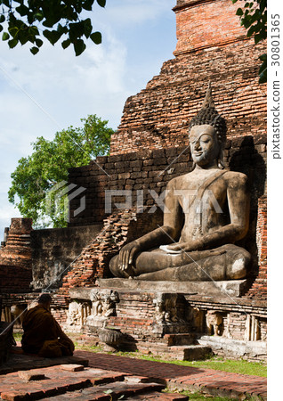 A monk meditating in front of buddhas statue large A monk meditating in front of buddhas statue large 30801365