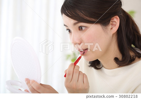 A woman applying lipstick A woman applying lipstick 30802218