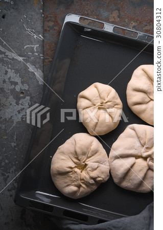Khachapuri with cheese on a baking sheet on a Khachapuri with cheese on a baking sheet on a 30804312