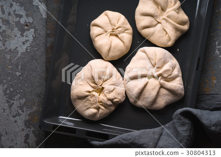 Khachapuri with cheese on a baking sheet on a Khachapuri with cheese on a baking sheet on a 30804313