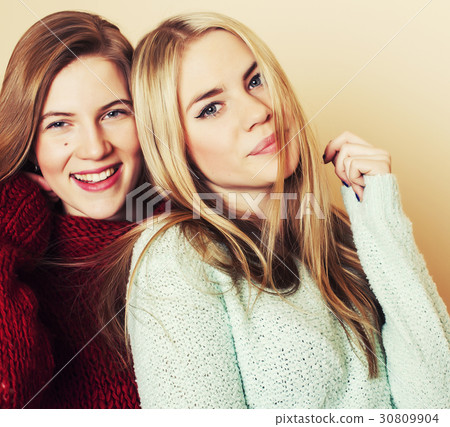 Two young girlfriends in winter sweaters indoors Two young girlfriends in winter sweaters indoors 30809904