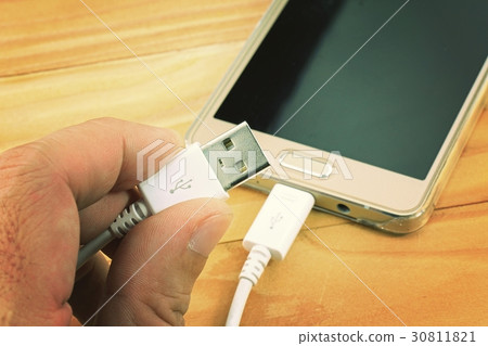 USB cable with smart phone on wood table. 30811821