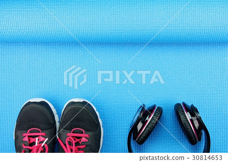 Headphones and sport shoes on yoga mat. 30814653
