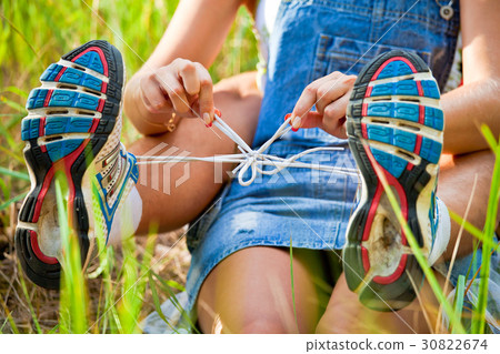 The girl ties laces on sneakers to the guy The girl ties laces on sneakers to the guy 30822674