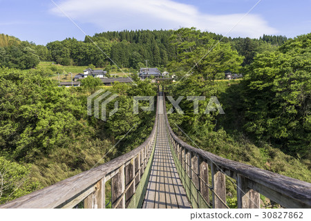 Suspension bridge over the waterfall of the hillside 30827862