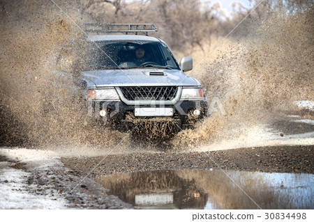 Mitsubishi Pajero Sport on dirt road in early spring making spla 30834498