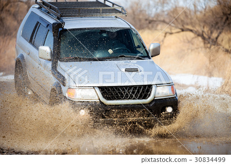 Mitsubishi Pajero Sport on dirt road in early spring making spla 30834499