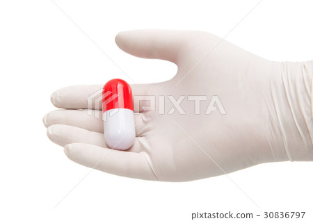 Hand holding a capsule or pill in medical gloves Hand holding a capsule or pill in medical gloves 30836797