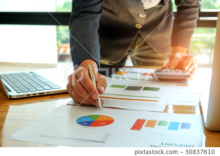 Businessman with using calculator analyzing graph. 30837610