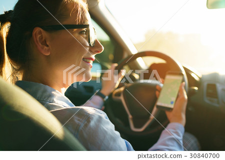 Happy woman uses a navigator in a smartphone while driving a car 30840700