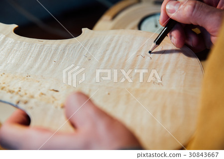 Master artisan luthier working on the creation of 30843667