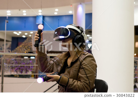 gir in VR headset with joysticks in hands engoying 30843822