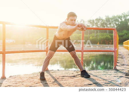 Young sporty man bending forward and doing 30844423