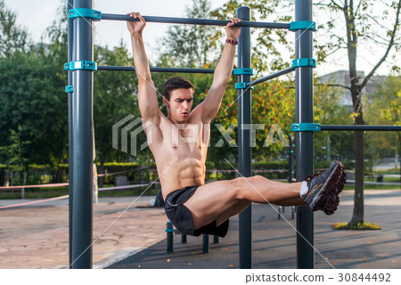 Athlete hanging on fitness station performing legs Athlete hanging on fitness station performing legs 30844492
