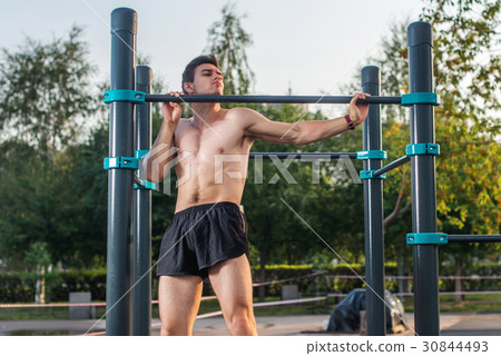 Young male athlete doing chin-up exercises in the Young male athlete doing chin-up exercises in the 30844493