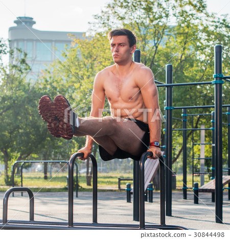 Young strong athlete working out in outdoor gym Young strong athlete working out in outdoor gym 30844498