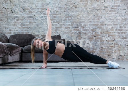 Strong Caucasian girl doing side plank exercise 30844668