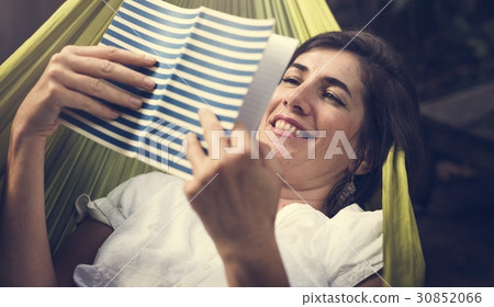 Woman lying on hammock chilling reading book 30852066