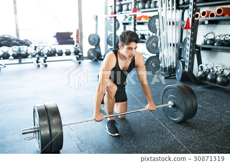 Young fit hispanic man in gym lifting heavy 30871319