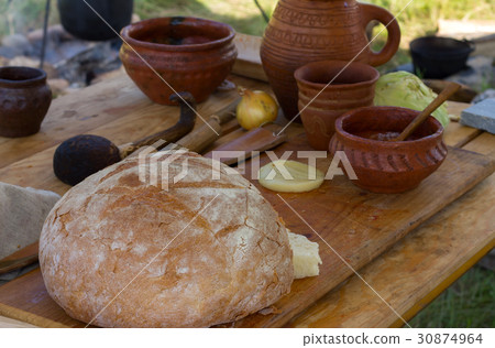 Ancient wooden clay dishes with bread on a table Ancient wooden clay dishes with bread on a table 30874964