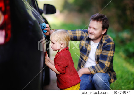 Middle age father with his toddler son washing car together outdoors 30874975
