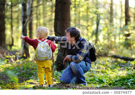 Father and his little son walking during the hiking activities in forest at sunset Father and his little son walking during the hiking activities in forest at sunset 30874977