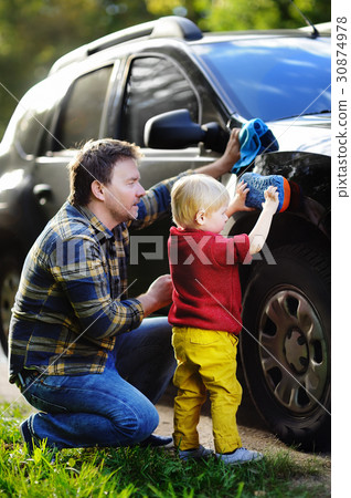 Middle age father with his toddler son washing car together outdoors Middle age father with his toddler son washing car together outdoors 30874978