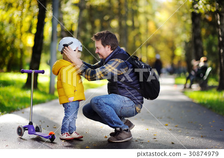 Middle age father helping his little son to put his helmet 30874979