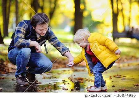 Middle age father playing with his toddler son together in a autumn park 30874980