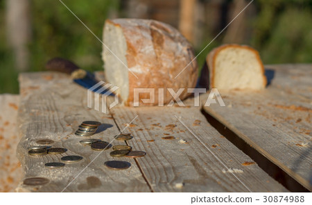Bread on a table with coins and knife Bread on a table with coins and knife 30874988
