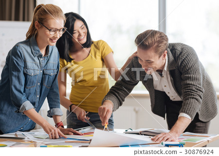 Positive happy designers standing around the table 30876924