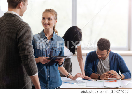 Joyful positive woman talking to her colleague Joyful positive woman talking to her colleague 30877002