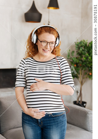 Cheerful woman smiling and holding hands on belly Cheerful woman smiling and holding hands on belly 30878191