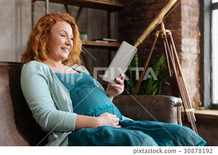 Cheerful mother-to-be reading book at home Cheerful mother-to-be reading book at home 30878192