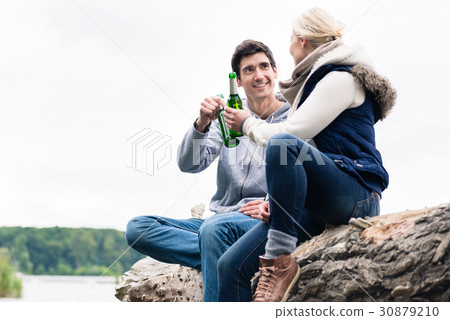 couple sitting on tree stump at the riverside 30879210
