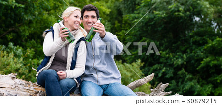 Lovers in vacation sitting at waterside clinking 30879215