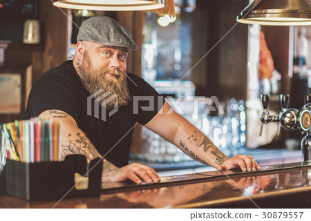 Bearded obese guy standing at workplace in pub Bearded obese guy standing at workplace in pub 30879557