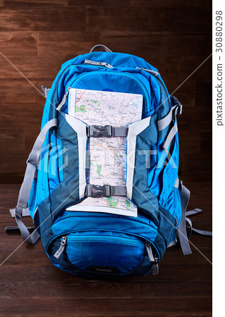 Tourist blue big backpack and map against wooden 30880298