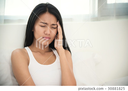 Asian woman having headache on her bed. Asian woman having headache on her bed. 30881825