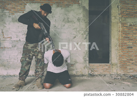 Terrorist in balaclava threatening with gun to man 30882804